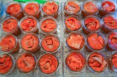 several jars filled with red food sitting on top of a metal tray next to a green spatula