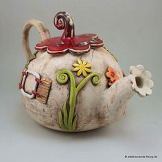 a ceramic teapot decorated with flowers and birds