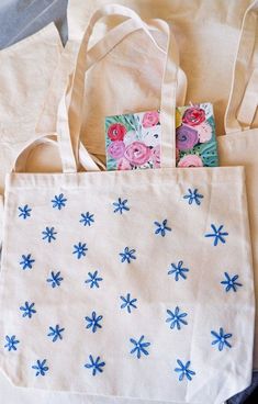 two bags with blue flowers on them sitting next to each other and one has a small piece of paper in it