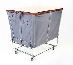 a large gray shopping cart with wheels and a brown handle on the top is shown