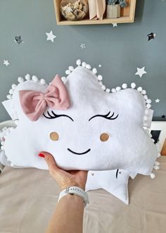 a person holding up a pillow with a bow on it's head and eyes