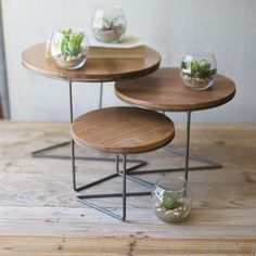 two tables with plants on them sitting on top of a wooden table