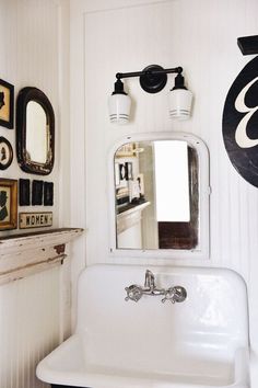 a white sink sitting under a bathroom mirror next to a wall mounted faucet