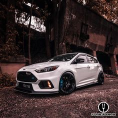 a white ford focus st parked in front of an old building with graffiti on it