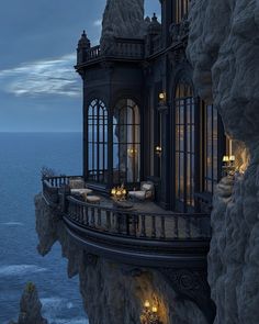 a house on top of a cliff overlooking the ocean at night with candles lit up