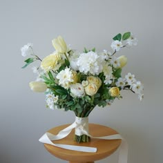 a bouquet of flowers sitting on top of a wooden table next to a white wall