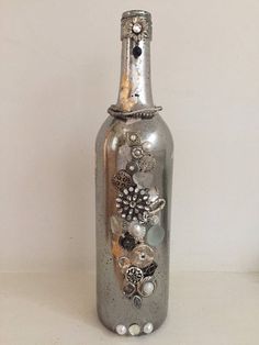 a silver bottle with flowers and pearls on it