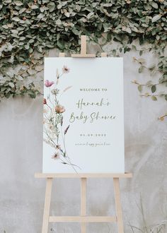 an easel with a sign that says welcome to the baby shower and flowers on it