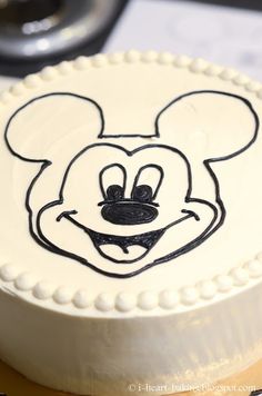 a mickey mouse cake with white frosting and black icing on it's face