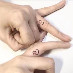 two fingers with hearts tattooed on them are pointing at each other's fingernails