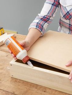 a person is painting the inside of a wooden box with orange paint and glue on it