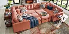 a living room with an orange sectional couch and colorful throw pillows on top of it