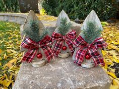 three wooden christmas trees with red and black bows on them sitting on a stone slab