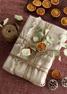 an orange slice tied to twine on top of a piece of cloth next to pine cones