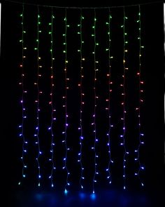 multicolored lights are hanging from the ceiling in front of a black backdrop with white curtains