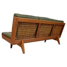 a wooden bench with green cushions sitting on it's legs and backrests