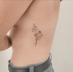 a woman's stomach with a small flower tattoo on her left side ribcage