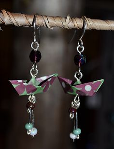 two origami cranes are hanging from the end of a pair of dangling earrings