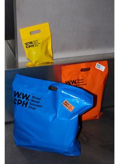 three different colored bags sitting next to each other on a table in front of a wall