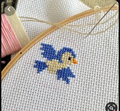 a close up of a cross stitch pattern on a piece of cloth with a needle and thread