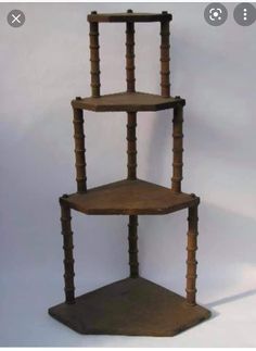 a three tiered wooden shelf sitting on top of a white floor next to a wall