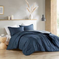 a bed with blue sheets and pillows in a room