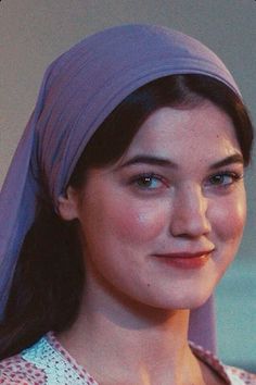 a woman wearing a purple turban smiles at the camera