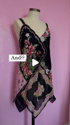 a mannequin wearing a black and pink dress with flowers on it, next to a pink wall