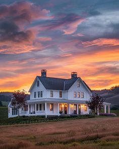 a large white house sitting on top of a lush green field under a cloudy sky