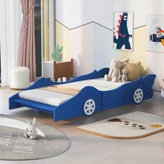 a child's bedroom with a blue car bed and rugs on the floor