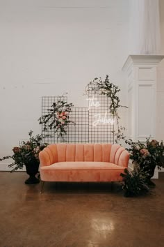 an orange couch sitting on top of a wooden floor next to potted planters