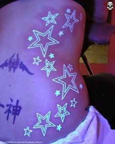 the back of a woman's stomach with stars painted on her body and writing written in purple ink