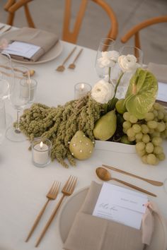 the table is set with white flowers, pears and other items for an elegant dinner