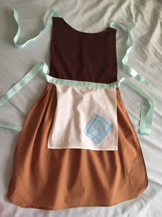 a brown and white dress with blue trims on the front, sitting on a bed