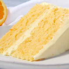 a slice of cake on a white plate with an orange wedge next to it,