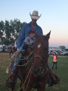 a man riding on the back of a brown horse with a little boy sitting on it