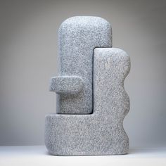 a large gray sculpture sitting on top of a white floor next to a wall mounted clock