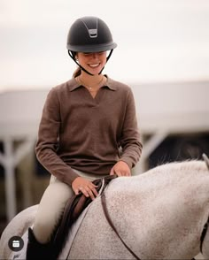 a smiling woman riding on the back of a white horse