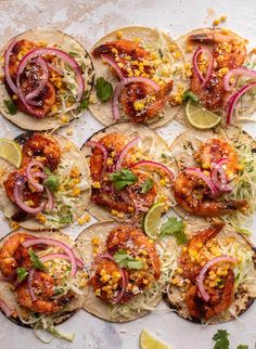 several tacos with shrimp, onions and cilantro on them are arranged on a sheet of parchment paper