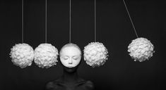 a black and white photo of a mannequin with five balls hanging from it's head