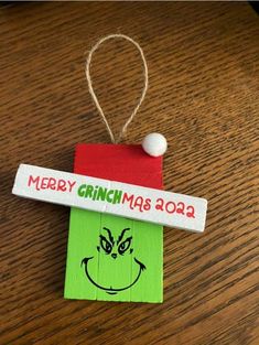 a christmas ornament hanging from a wooden table with a name tag on it