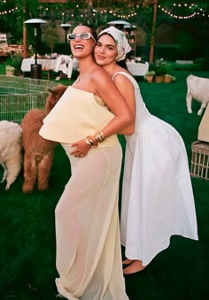 two women standing next to each other in front of some llamas at a wedding