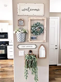 a wall with some plants and pictures hanging on it's side in a kitchen