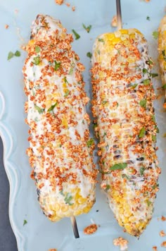 three corn on the cob with cheese and seasoning