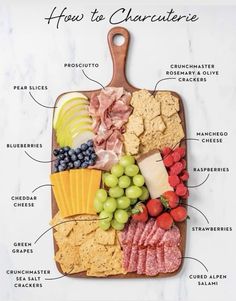 a cutting board with different types of cheeses, crackers and fruit on it