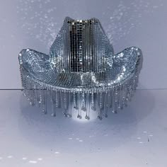 a shiny metal chair sitting on top of a white table covered in water droplets and rain drops