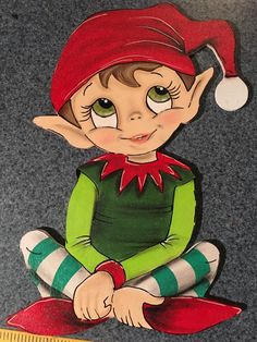 an elf sitting on the ground with a ruler in front of him and wearing a red hat