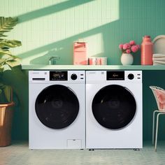 two washing machines sitting next to each other in front of a green tiled wall and potted plant