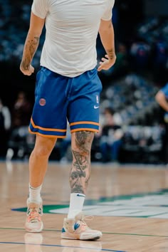 a man with tattoos on his arms and legs is standing in the middle of a basketball court