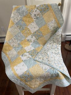 a quilted blanket sitting on top of a wooden stool in front of a door